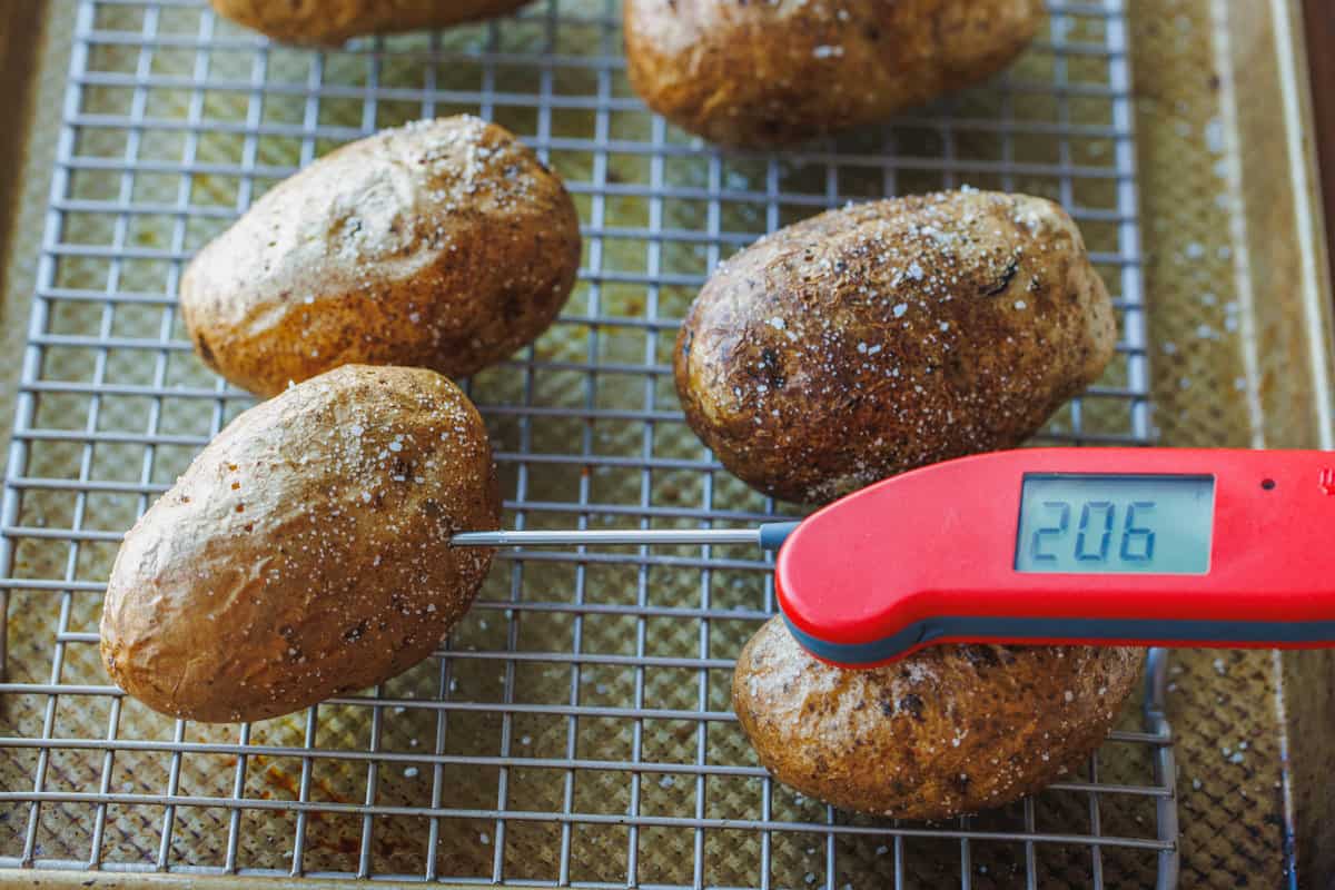 Checking baked potato with thermometer
