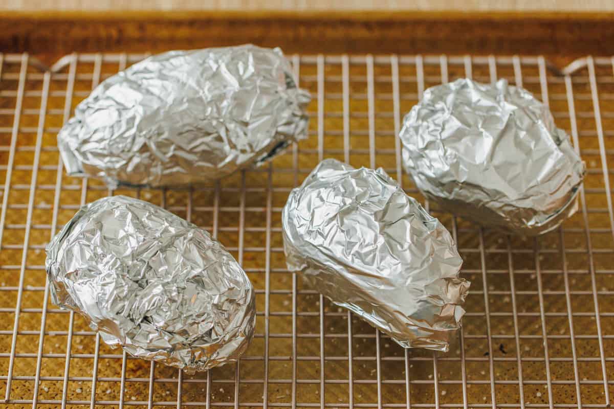 Potatoes wrapped in foil keeping warm inside the oven.