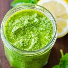 Basil pesto sauce in jar with fresh basil leaves and lemon