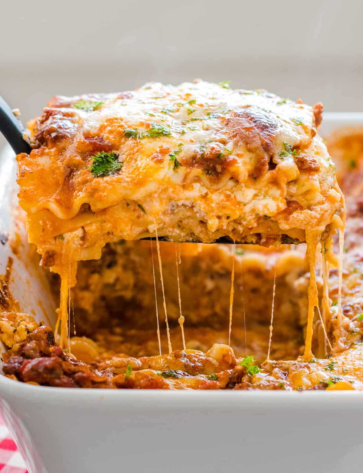 Piece of lasagna being lifted from baking dish