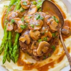 Salisbury steak with mushroom gravy served over mashed potatoes with asparagus